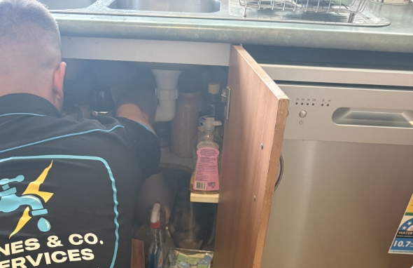 blocked kitchen Plumber working underneath kitchen sink waste